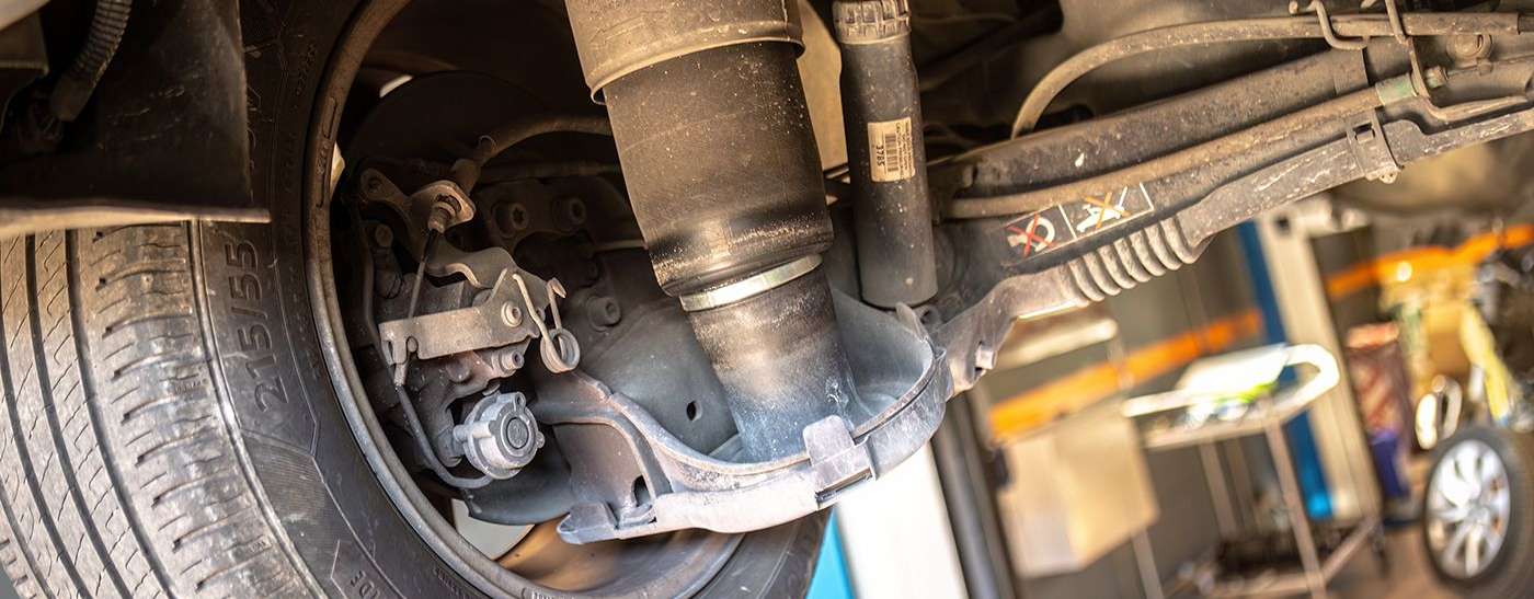 Undercarriage of a vehicle with a visible air suspension, rear tire and other mechanical components.