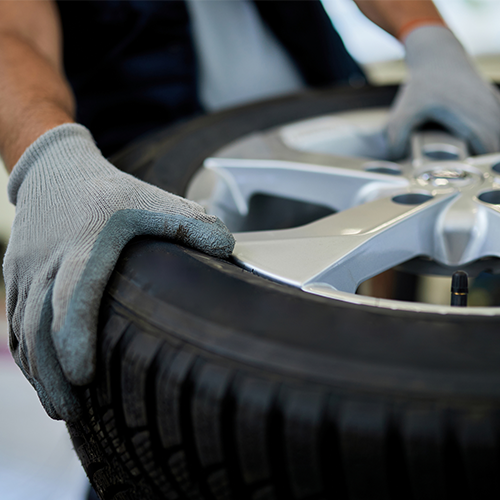 A person wearing gloves is putting a tire on a wheel