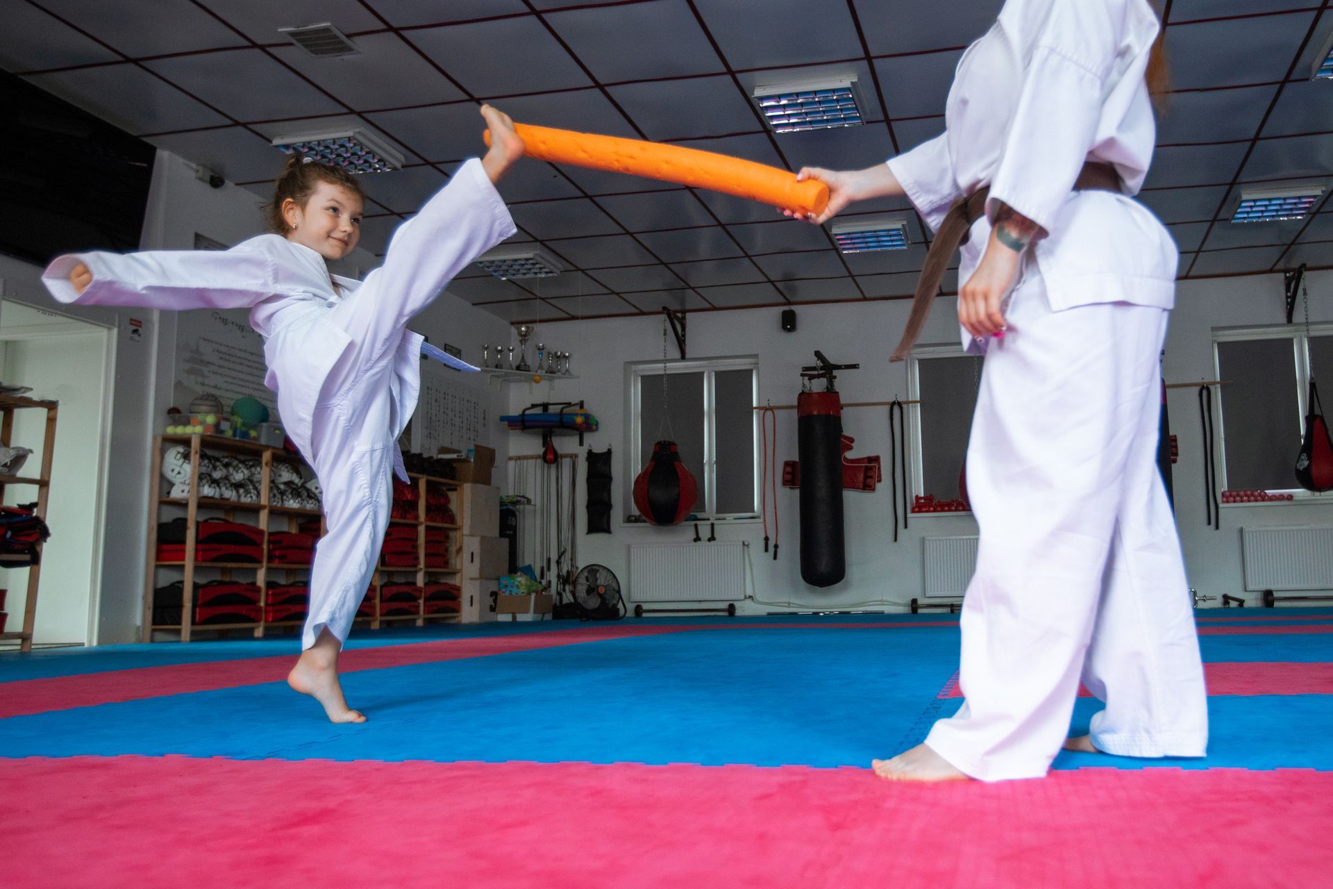 A girl training in karate with an orange stick, highlighting her dedication to martial arts classes. A girl training in karate with an orange stick, highlighting her dedication to martial arts classes.