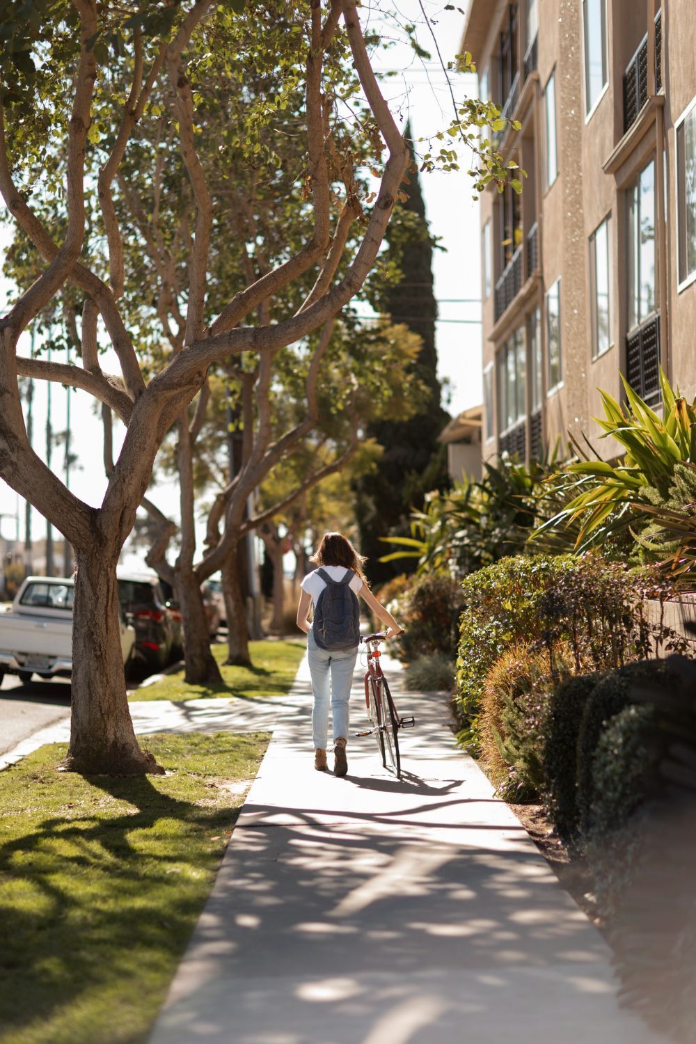 A person is walking down a sidewalk with a bicycle.