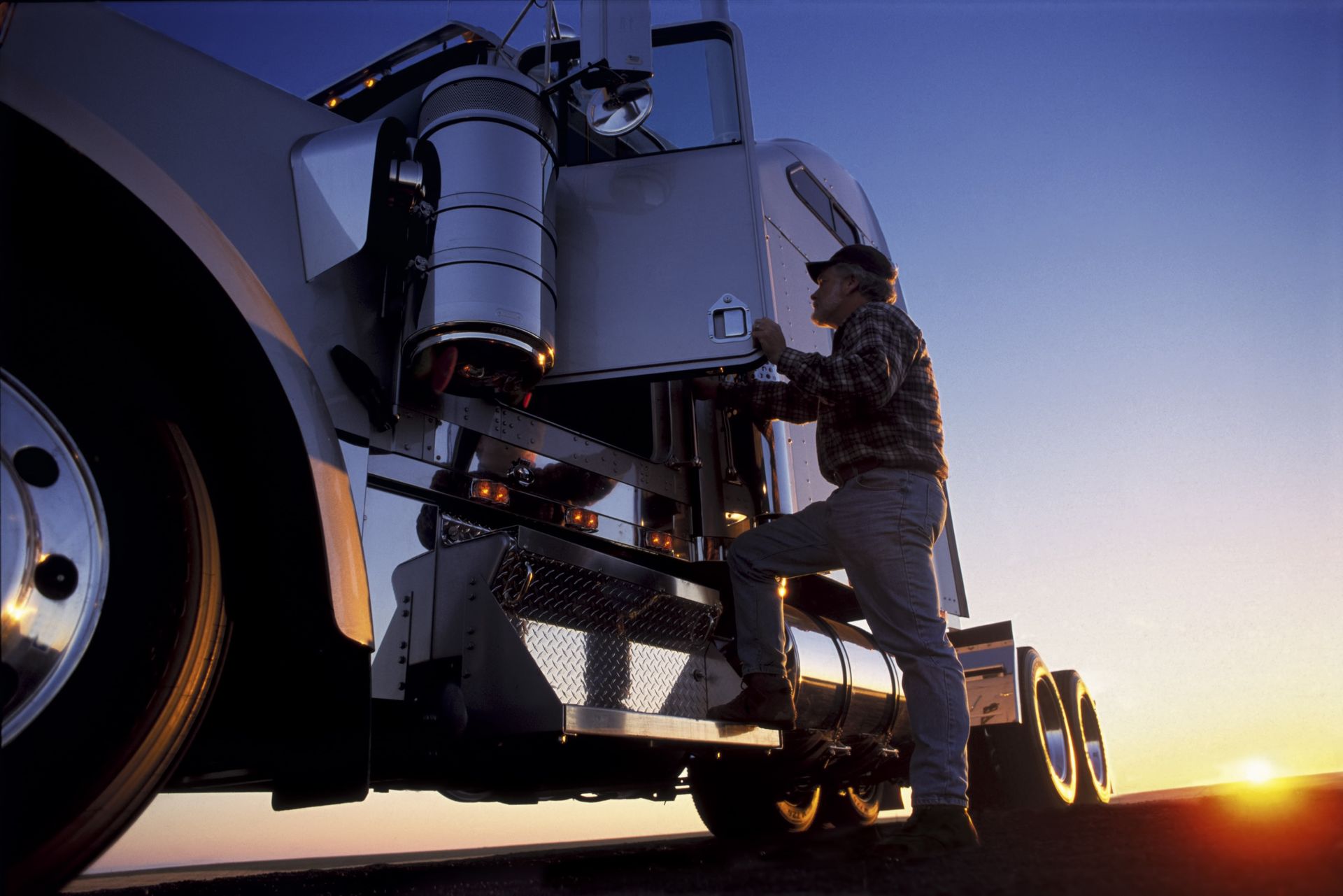 A man is standing on the steps of a semi truck.