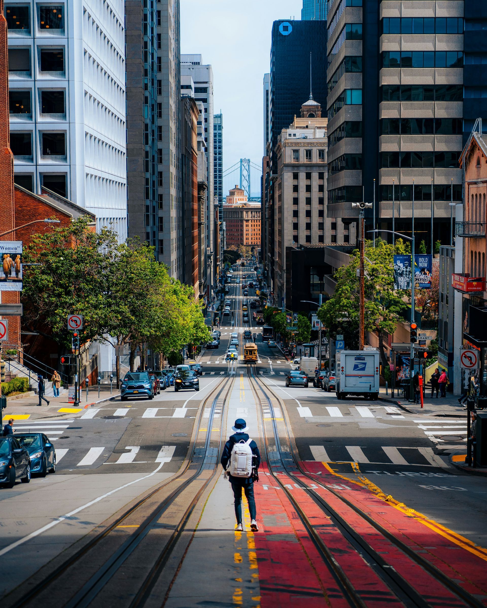 A man with a backpack is walking down a city street.