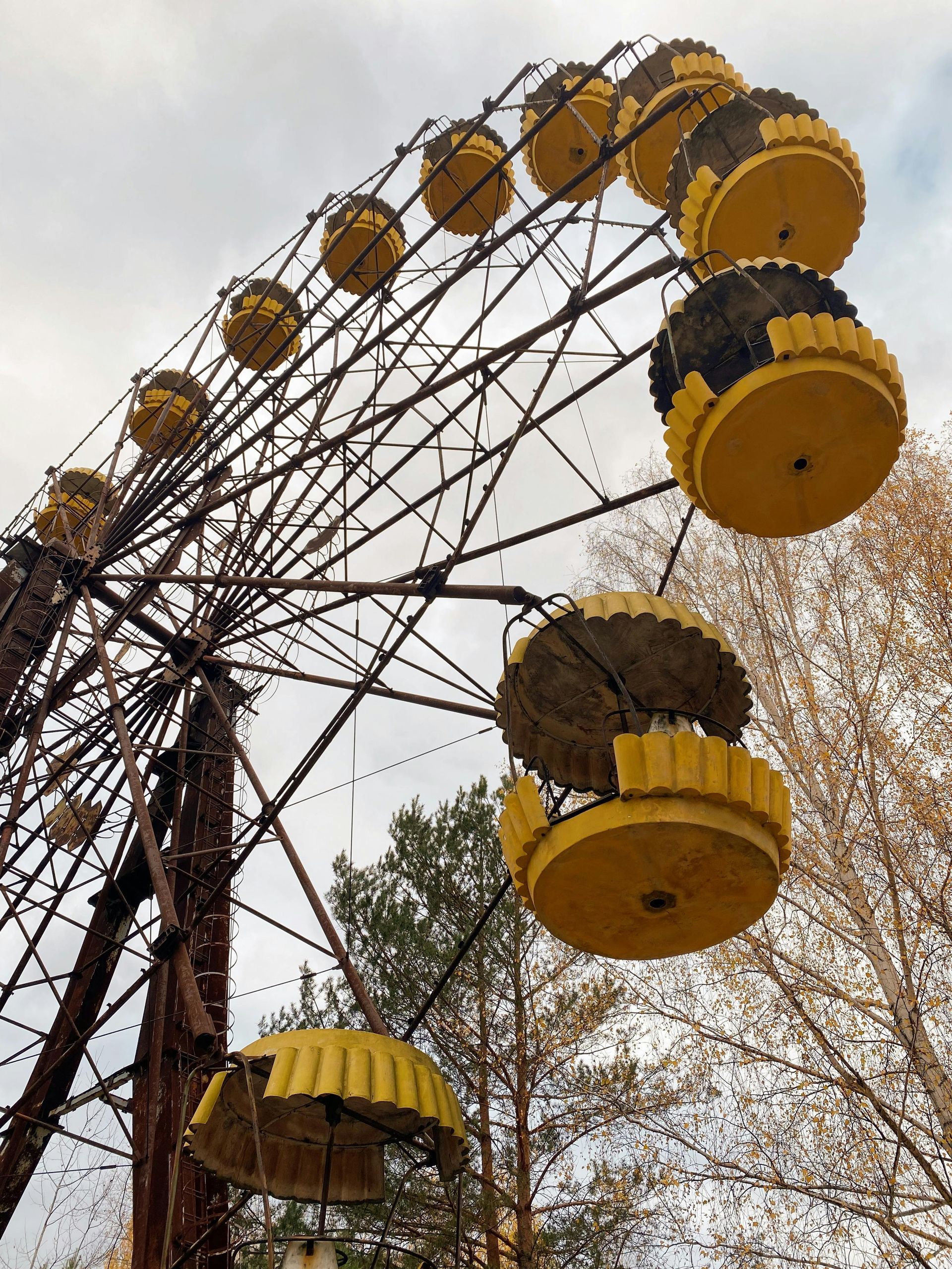 A yellow and black ferris wheel with trees in the background