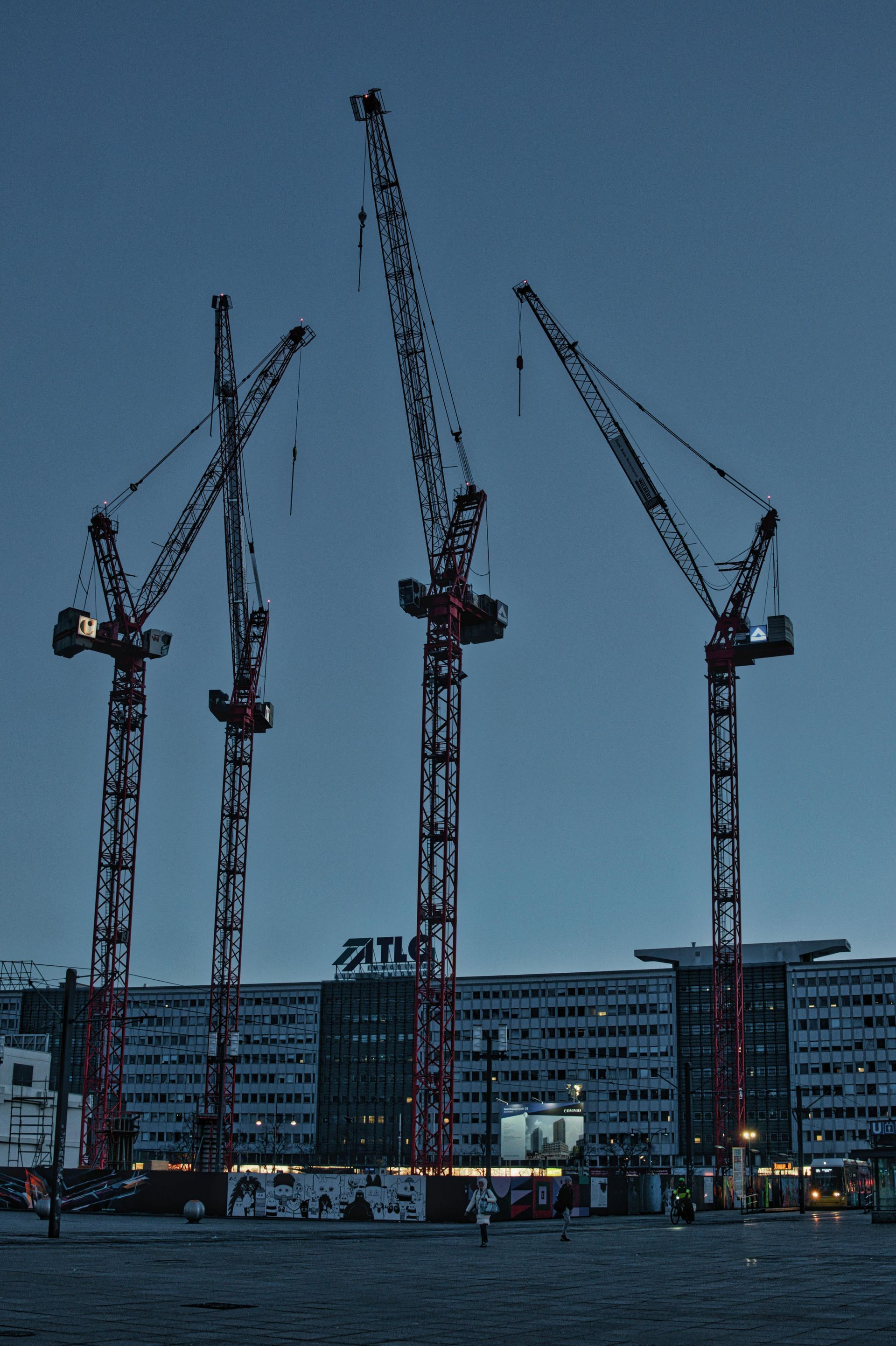 A group of construction cranes are lined up in front of a building