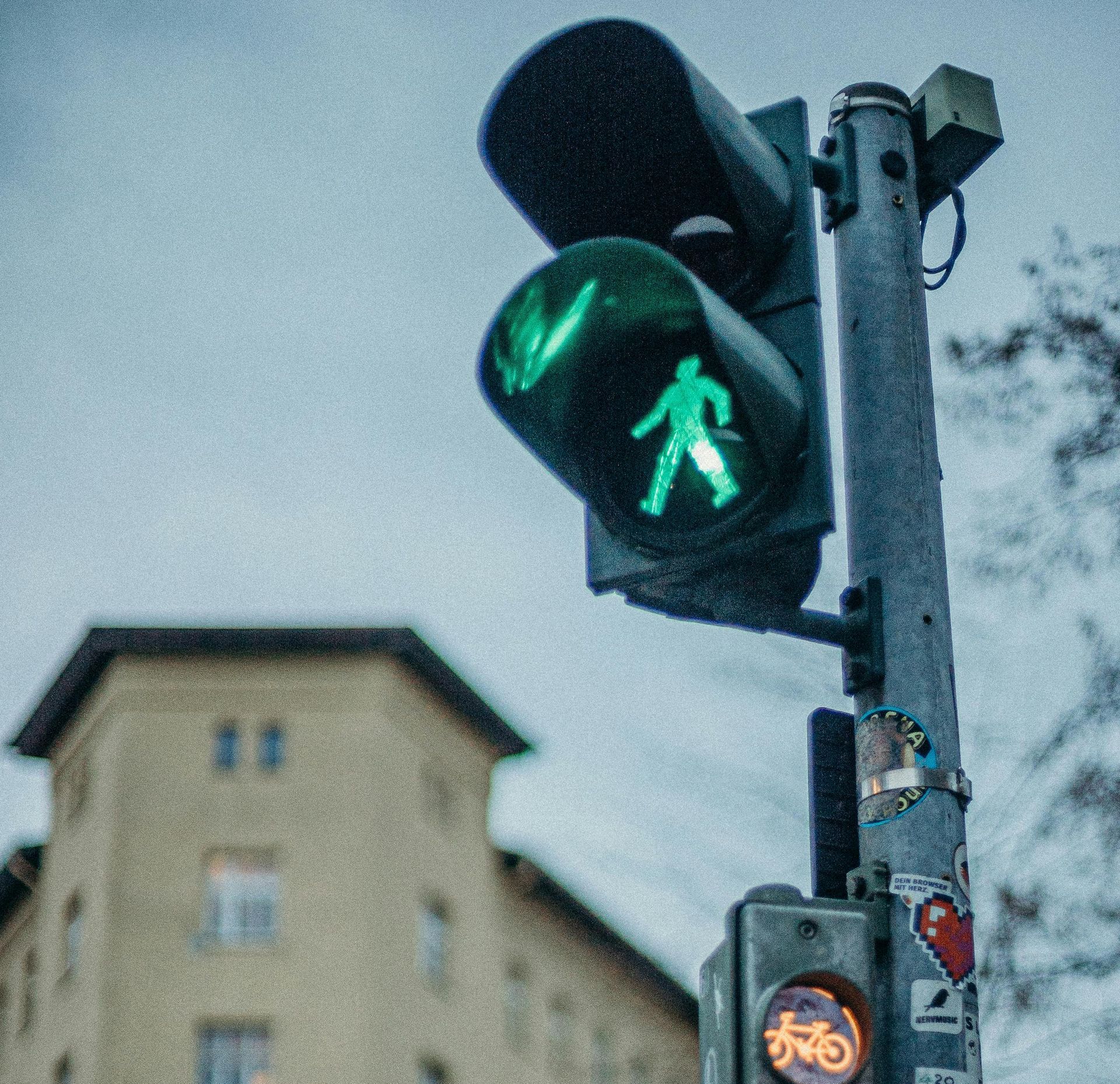 A green pedestrian crossing light with a building in the background