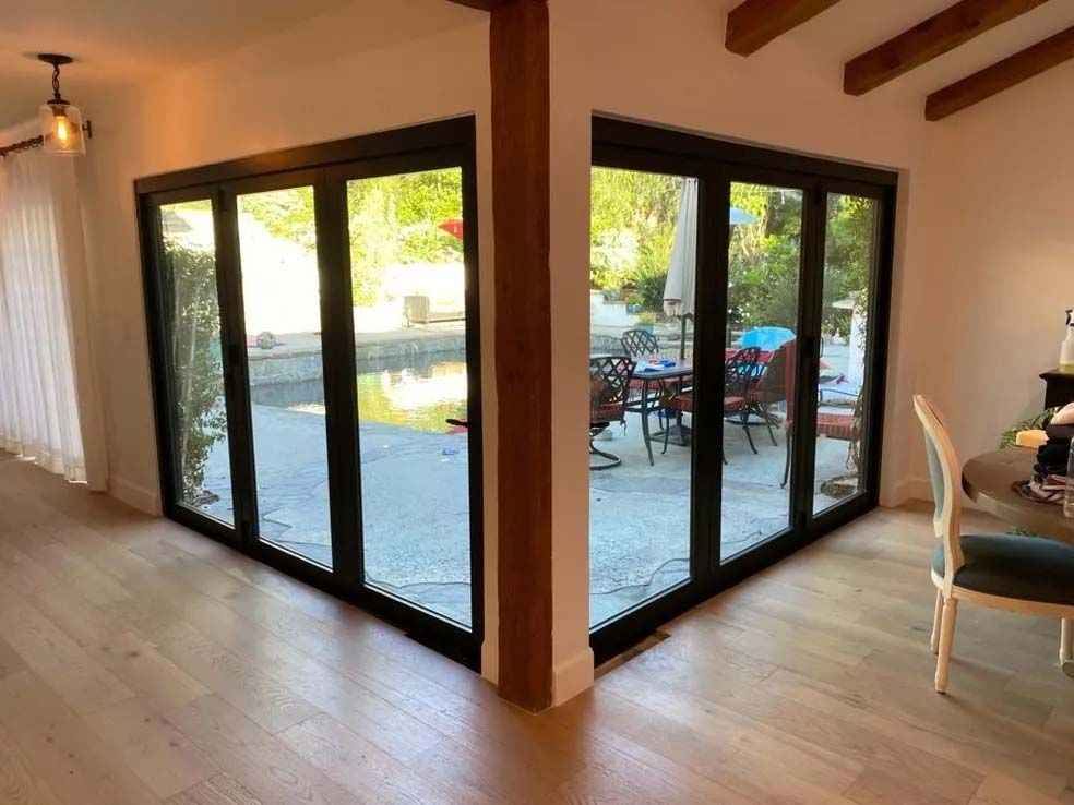A living room with a lot of windows and a table and chairs.