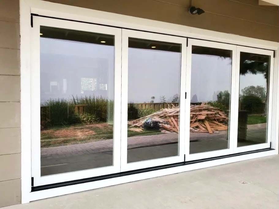 A white sliding glass door with a lot of windows on a house.