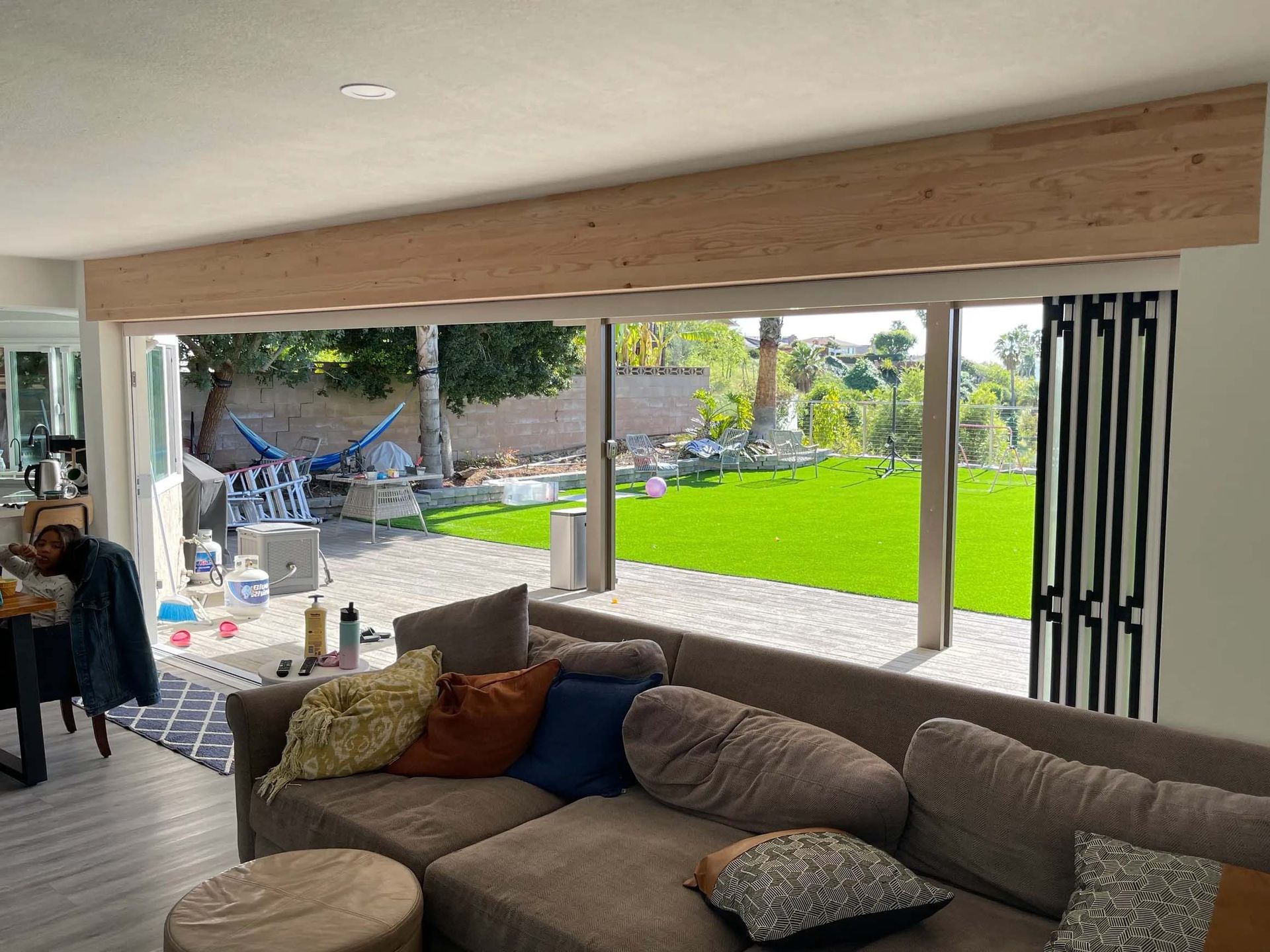 A living room with a couch and ottoman and a view of a backyard.