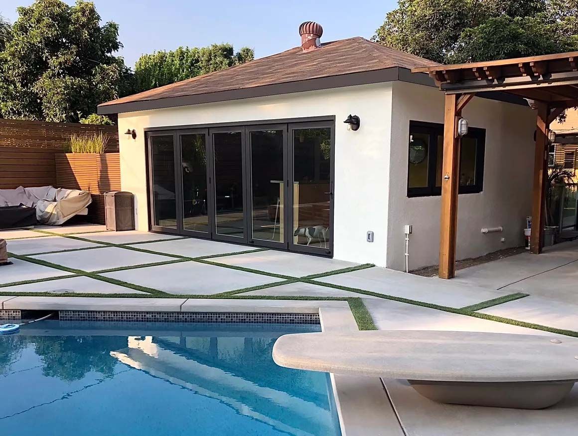A white house with a swimming pool in front of it.
