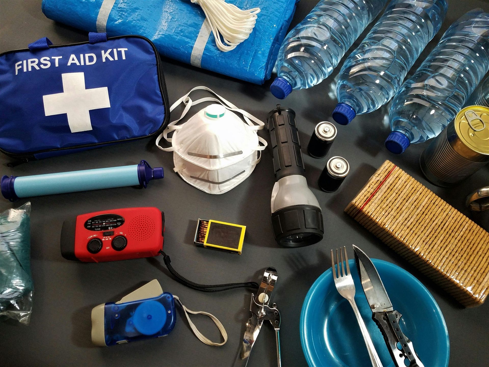 Emergency preparedness kit with water, first aid, food, and protective gear.