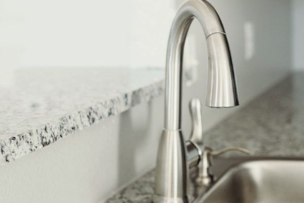 Stainless steel kitchen faucet over granite countertop.