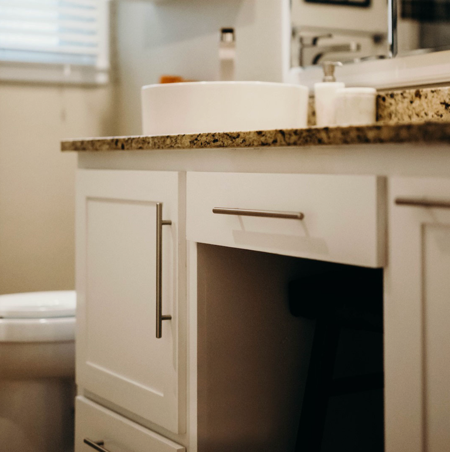 White bathroom vanity with a sink, countertop, and open space for storage.