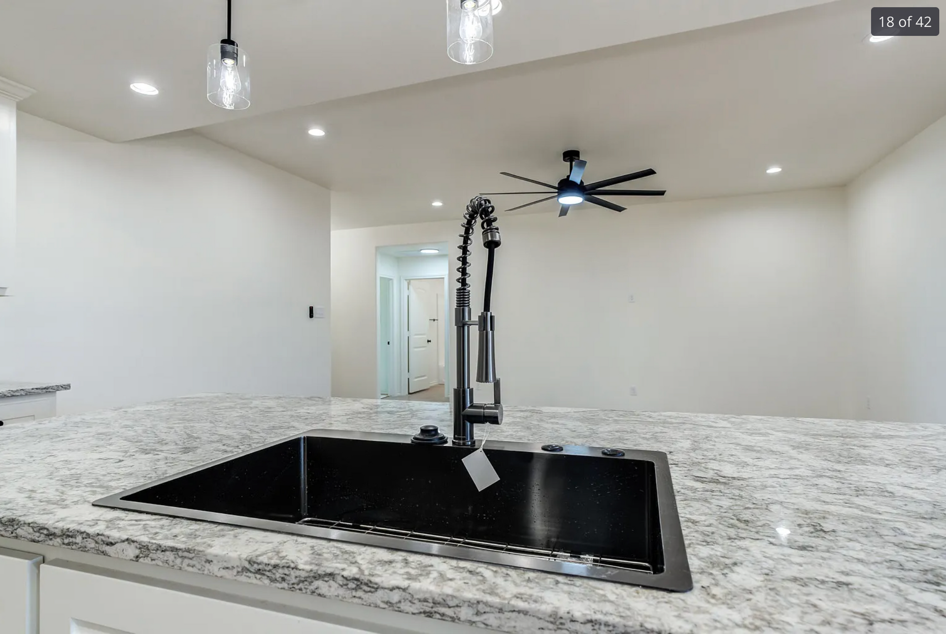 Kitchen with granite countertop, black sink, and black faucet. White walls and recessed lighting.