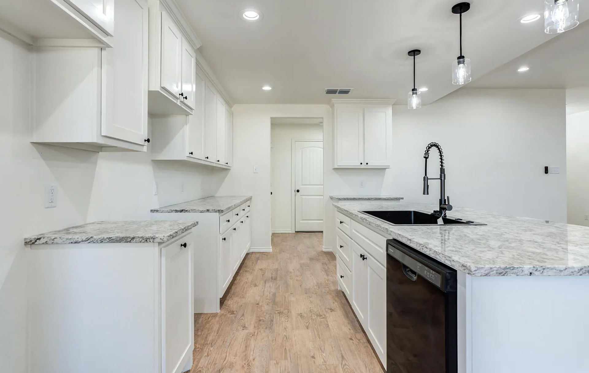White laundry room with brick-like backsplash, white cabinets, wooden countertop and dark hexagonal floor tiles.