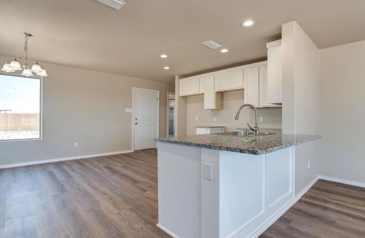 Laundry room with white cabinets, brick tile, dark countertops, and patterned floor.