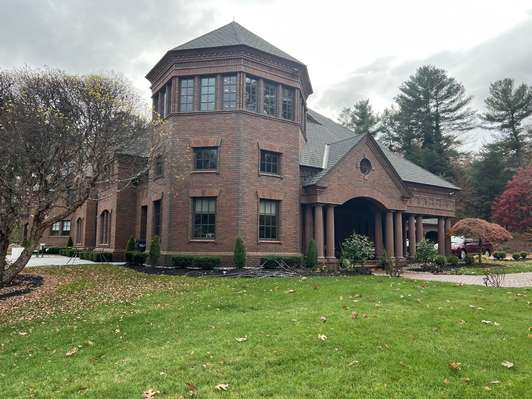 A large brick house with a circular roof is sitting on top of a lush green lawn.