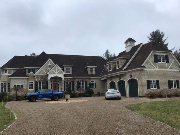 A blue truck is parked in front of a large house