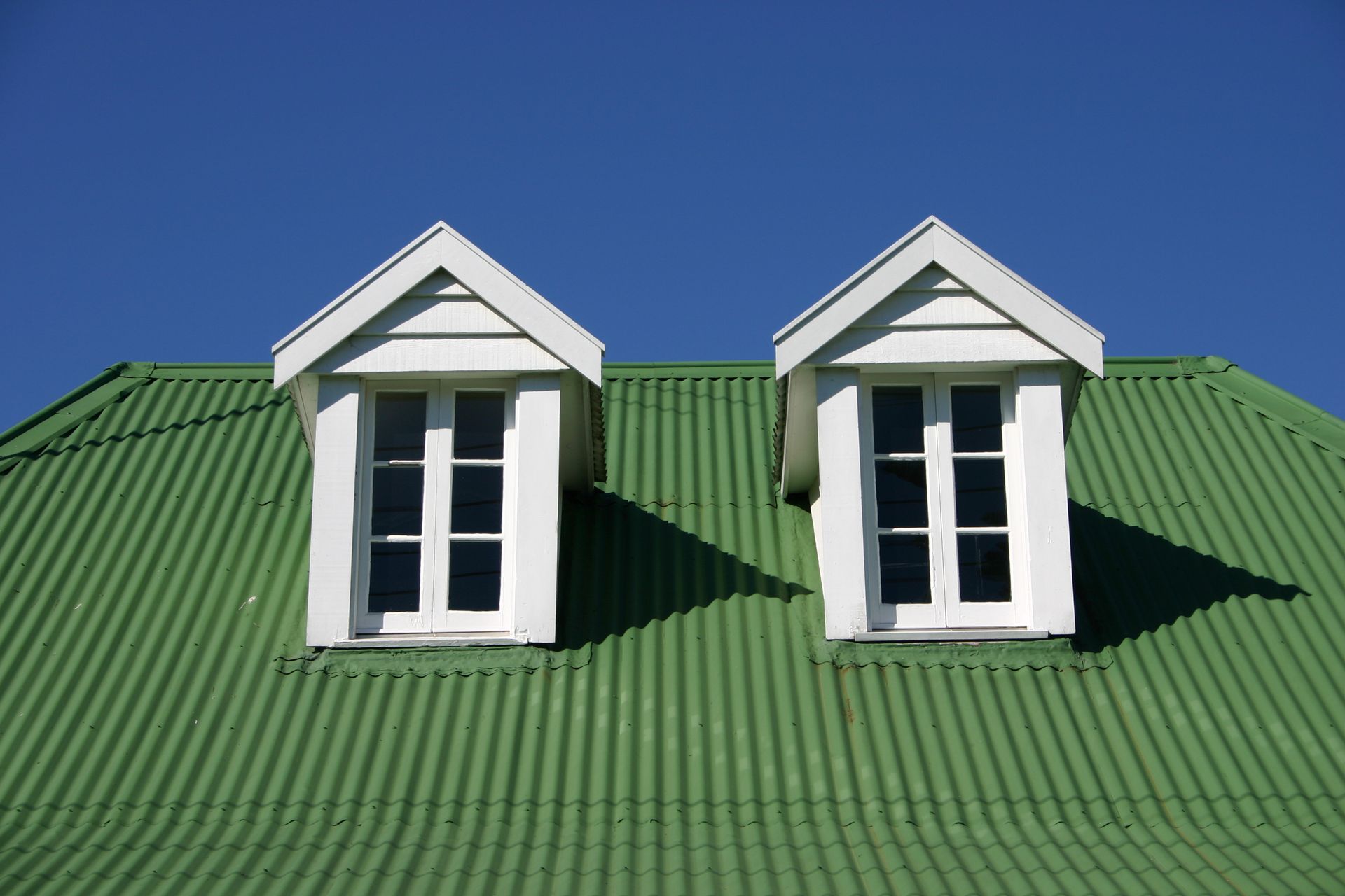 A green roof with two white windows on it