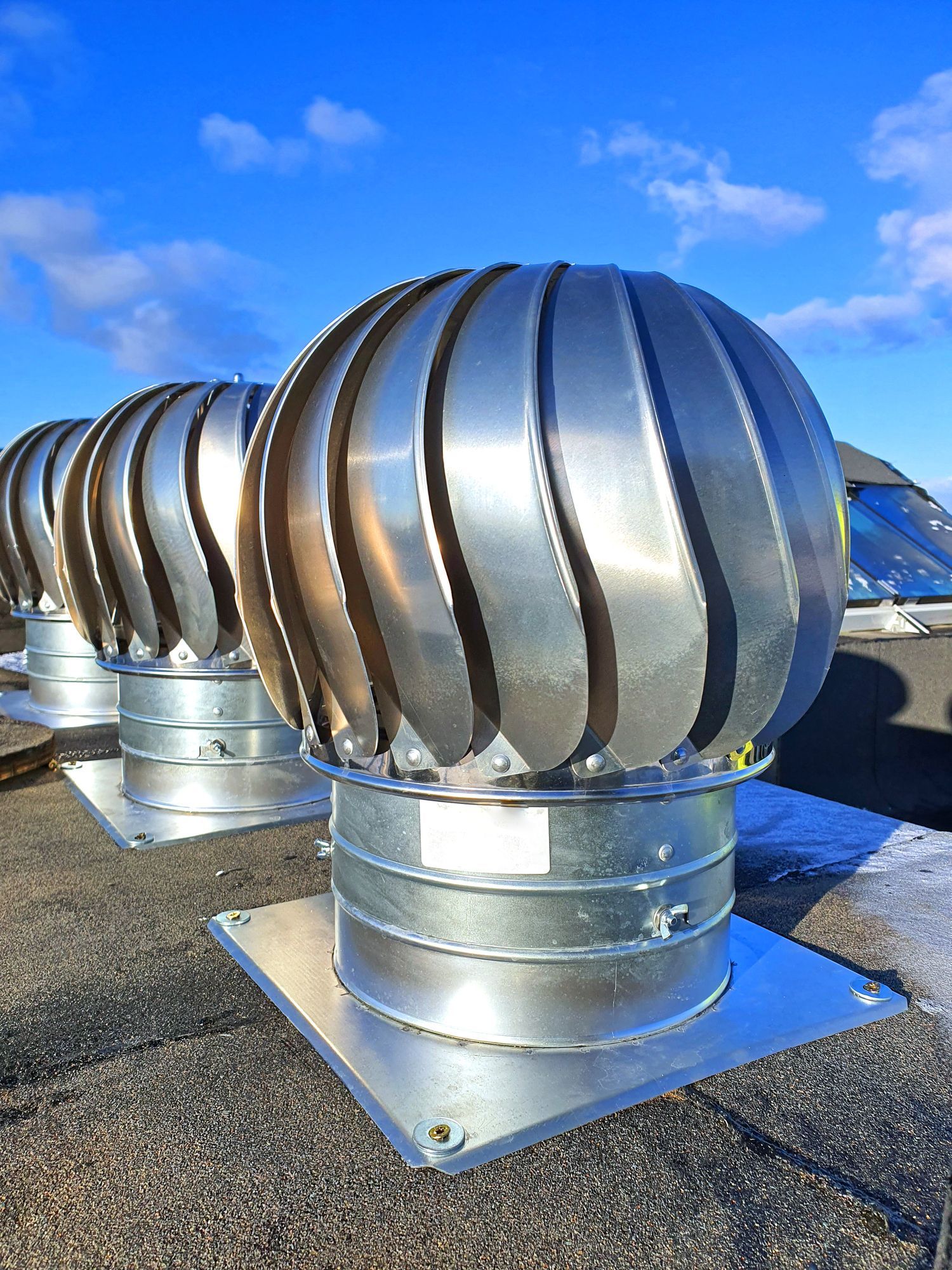 A row of metal exhaust fans are sitting on top of a roof.
