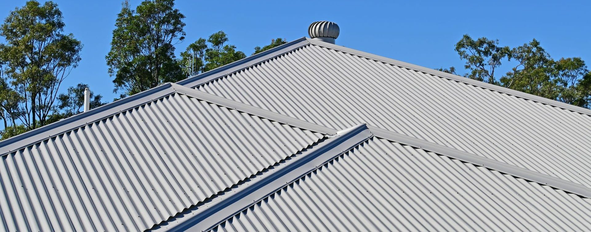 A white corrugated metal roof with trees in the background.