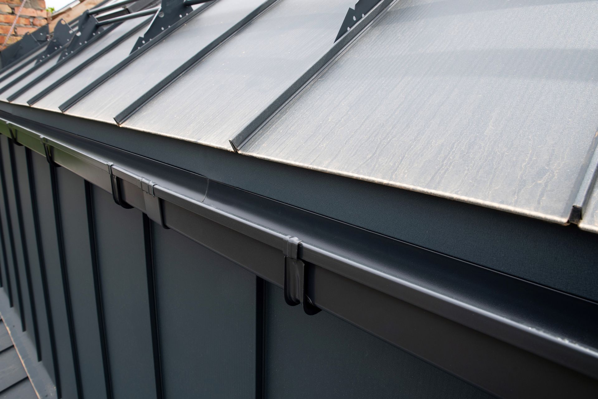 A close up of a metal roof with a black gutter