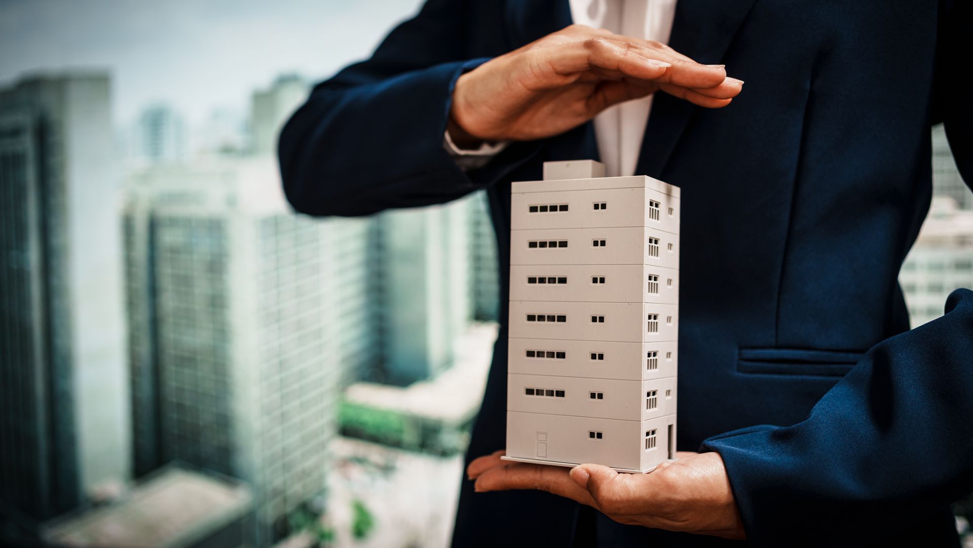 Commercial property manager presenting a miniature building model.
