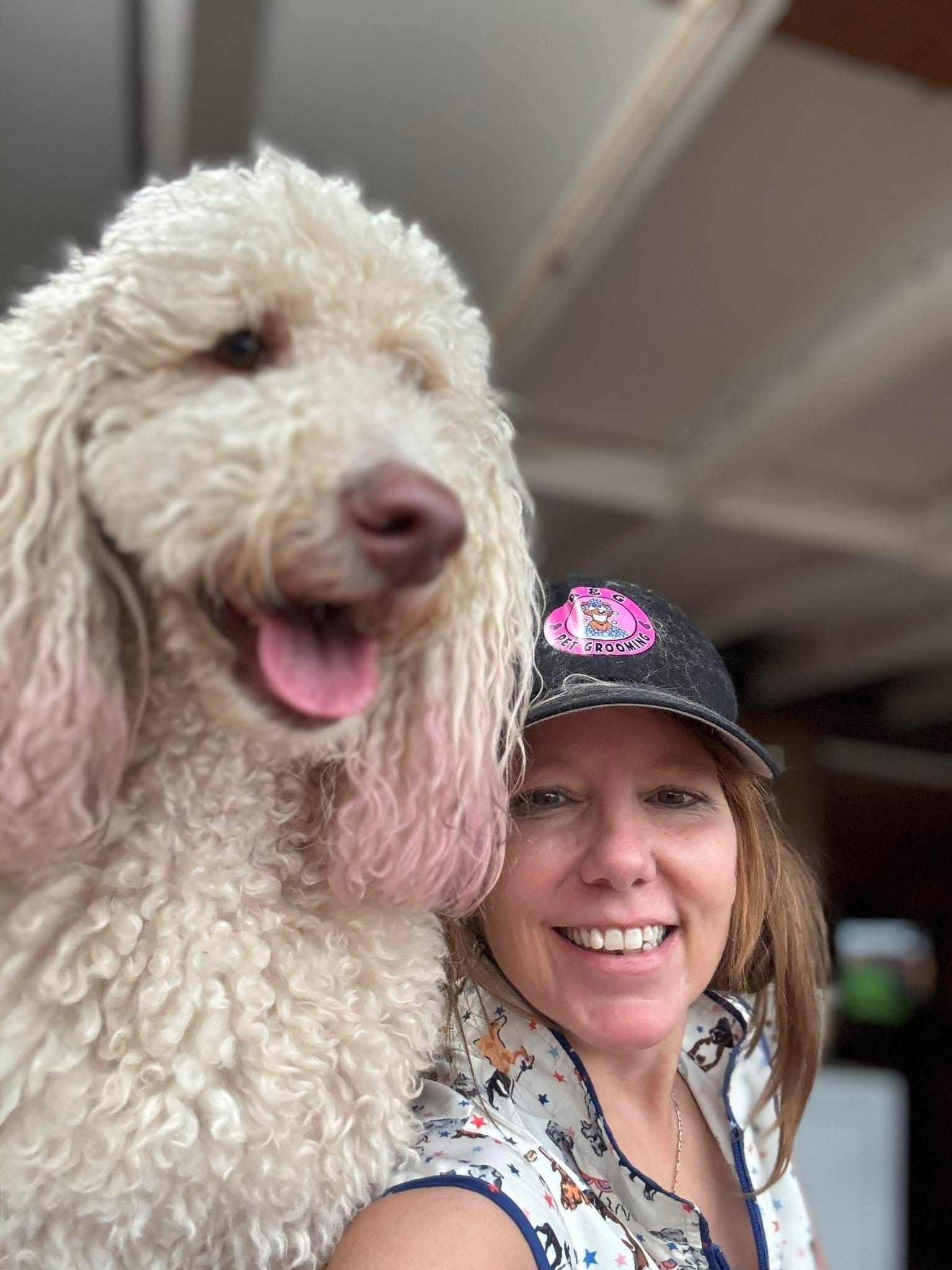 Woman smiles, taking a selfie with a dog, both facing the camera; outdoors, overcast.