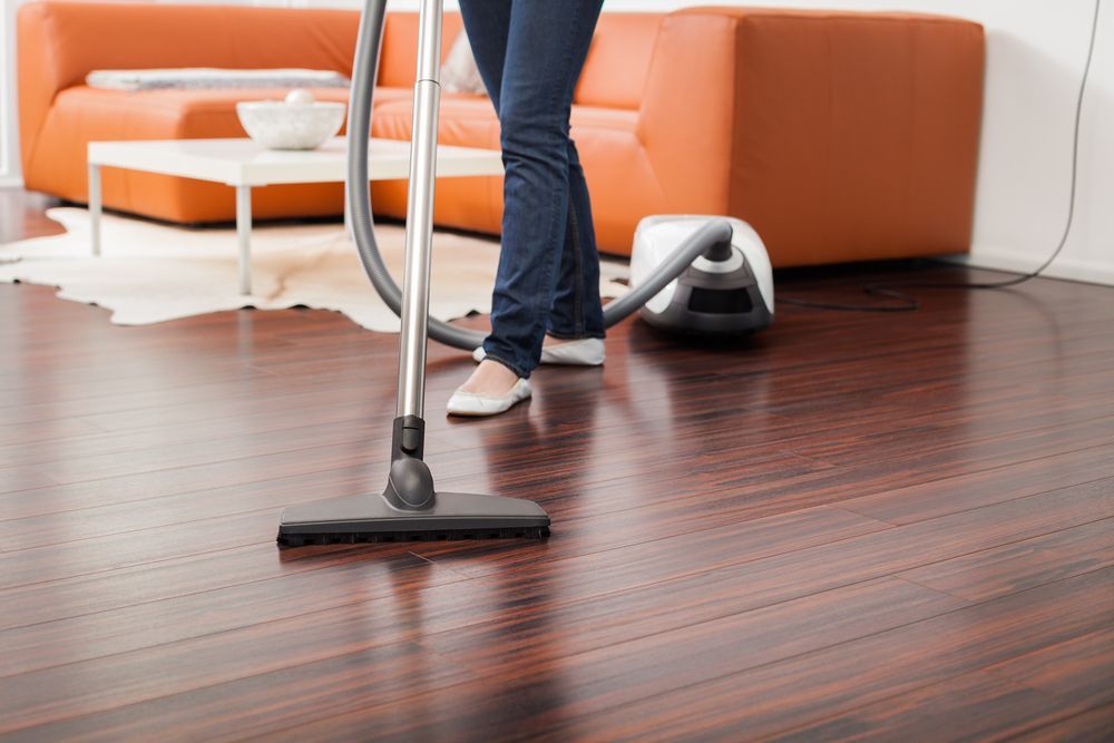 Person Vacuuming Hardwood Floor in a Living Room — All Sparkles Cleaning Technology In Proserpine, QLD