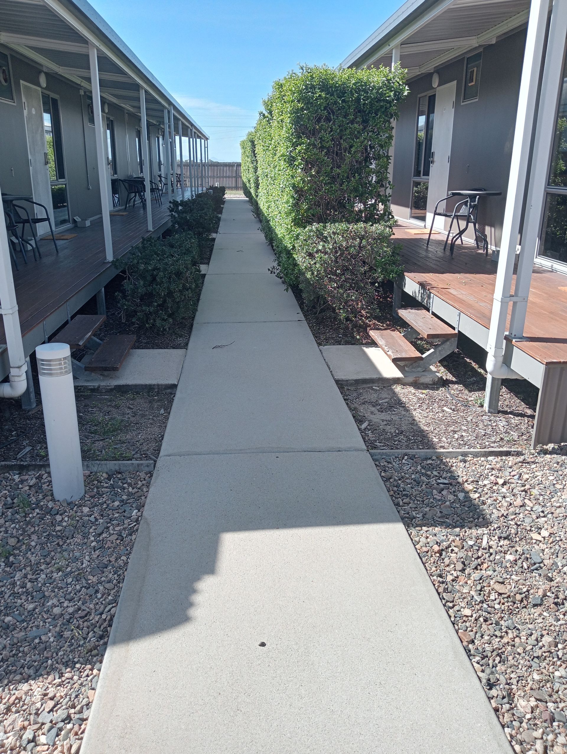 A Concrete Path Between Two Buildings With Porches — All Sparkles Cleaning Technology In Ayr, QLD