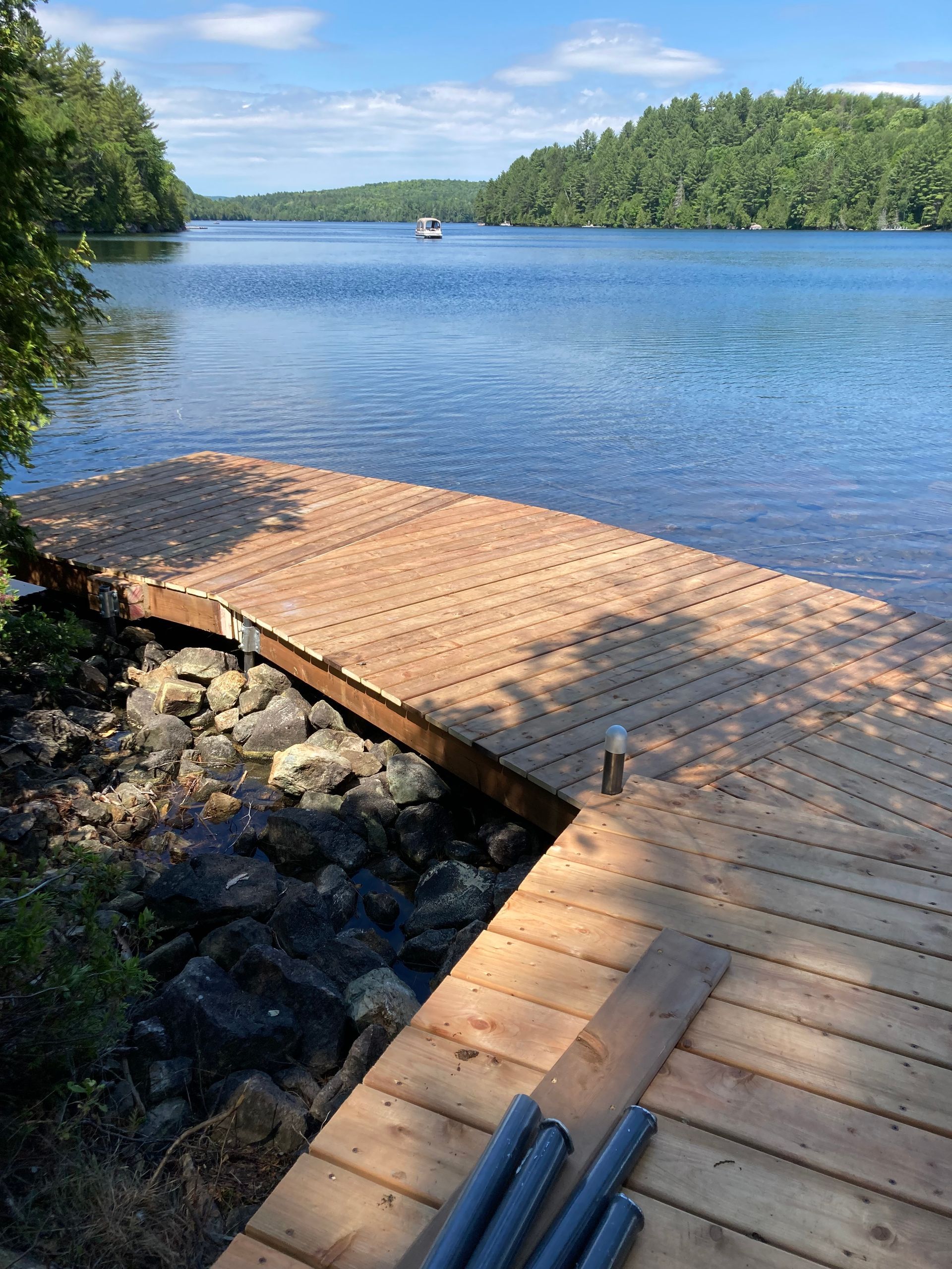 Un quai en bois surplombant un lac avec un bateau au loin.