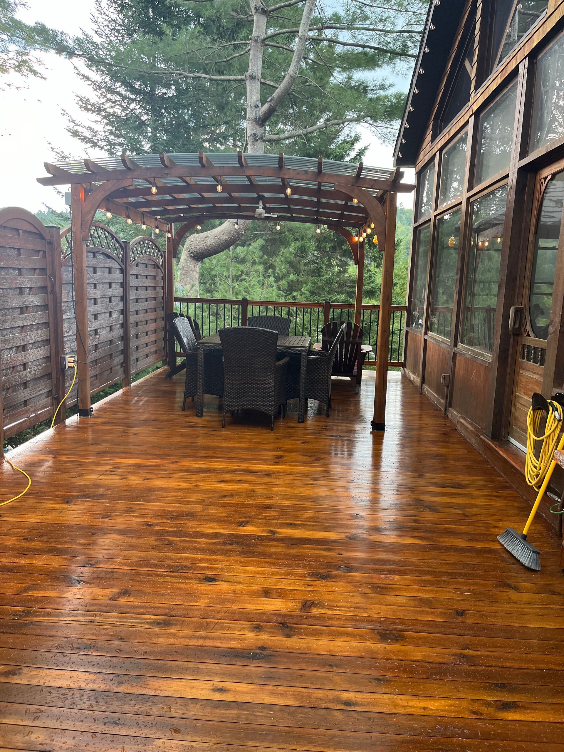 Une grande terrasse en bois avec une pergola et une table et des chaises dessus.