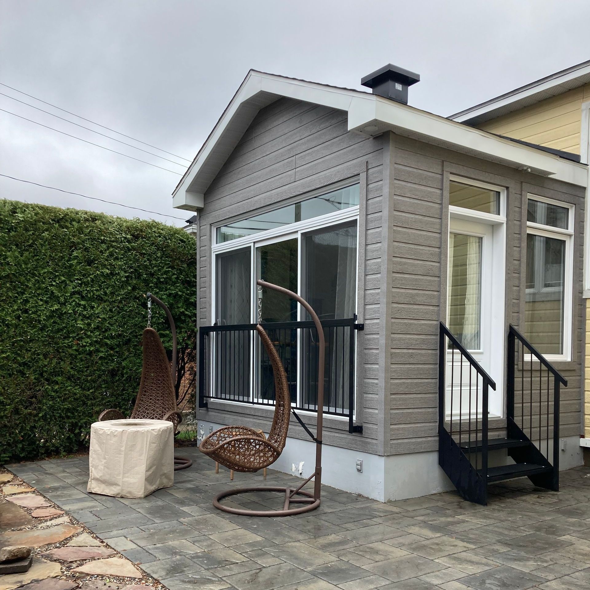 Une petite maison avec une chaise en osier devant