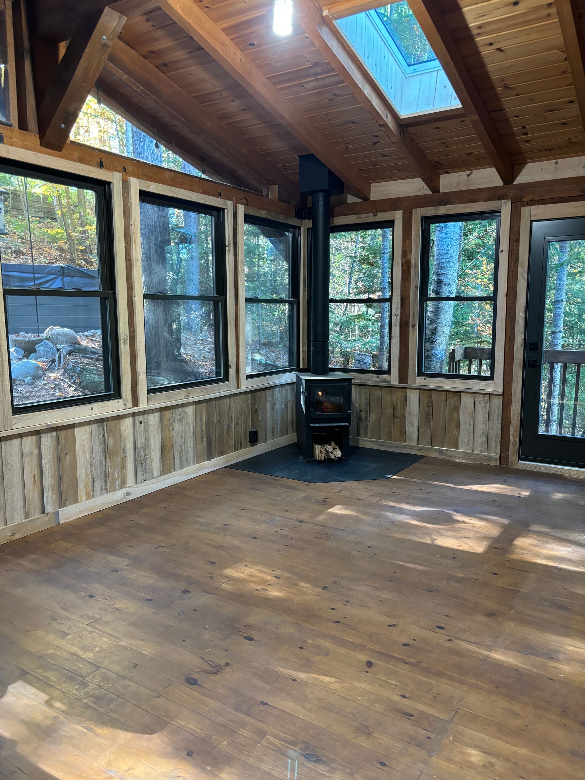 Une pièce vide avec un poêle à bois et beaucoup de fenêtres