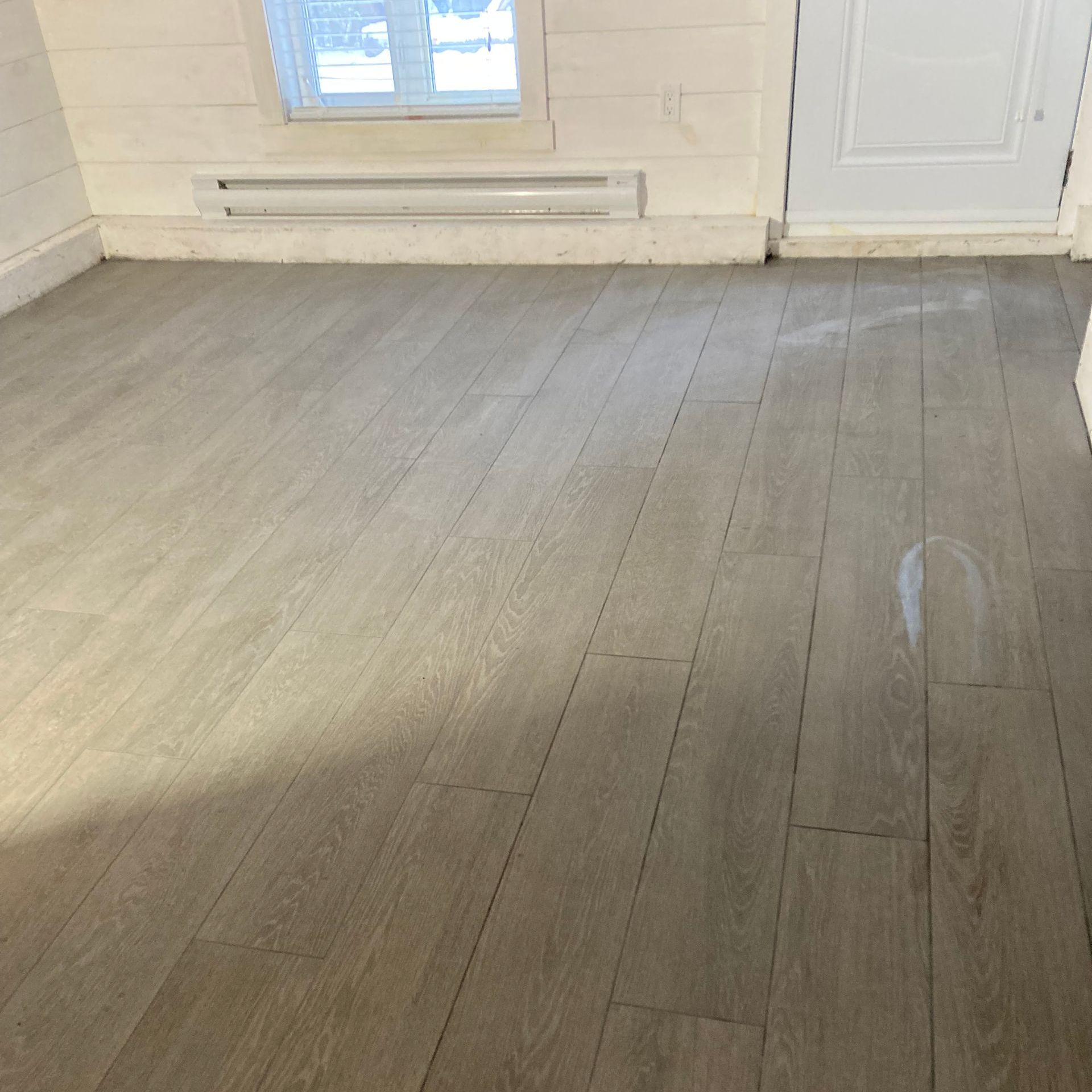 Une pièce avec un plancher en bois et une fenêtre.