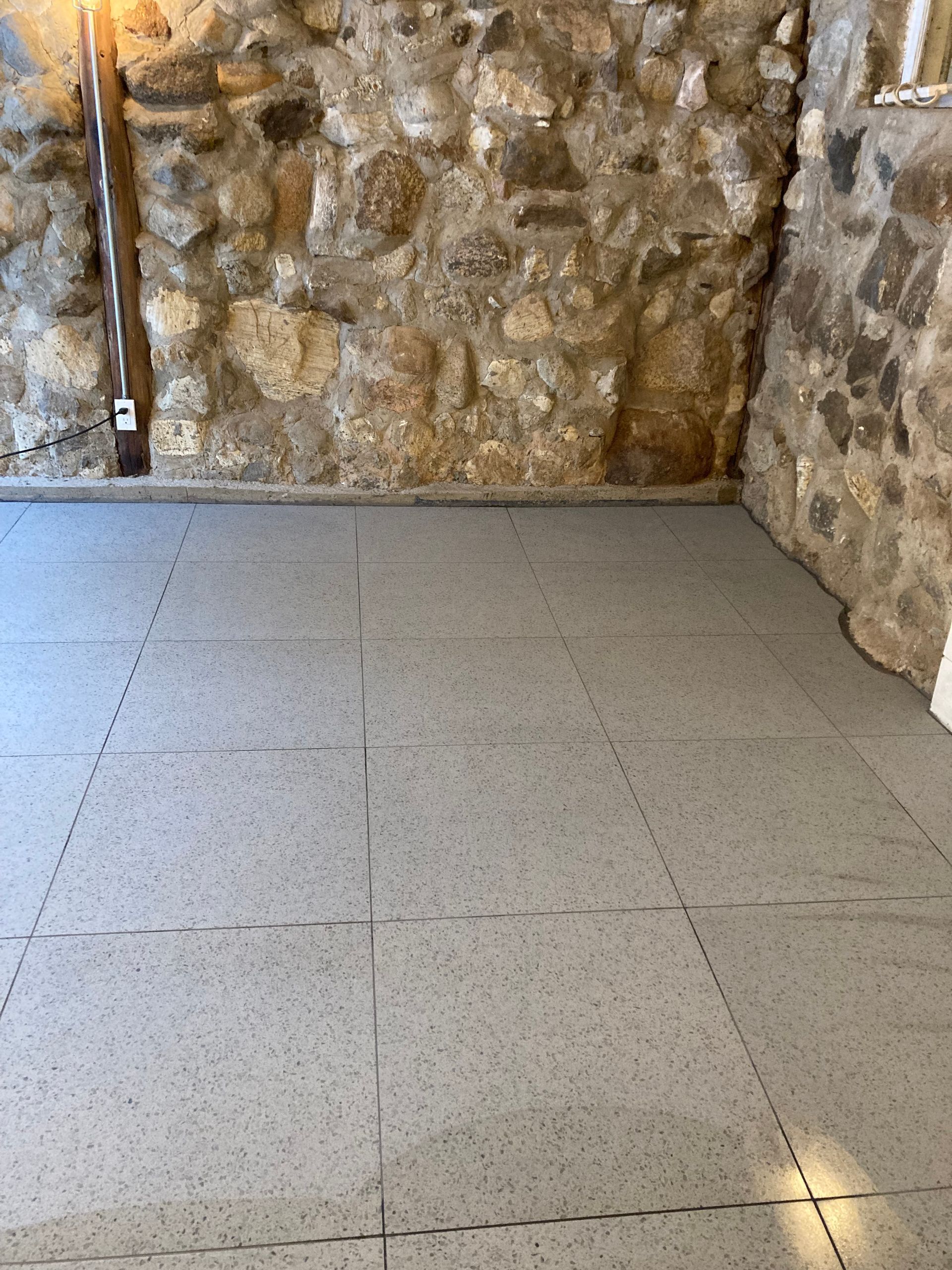 Une pièce avec un mur en pierre et un sol carrelé