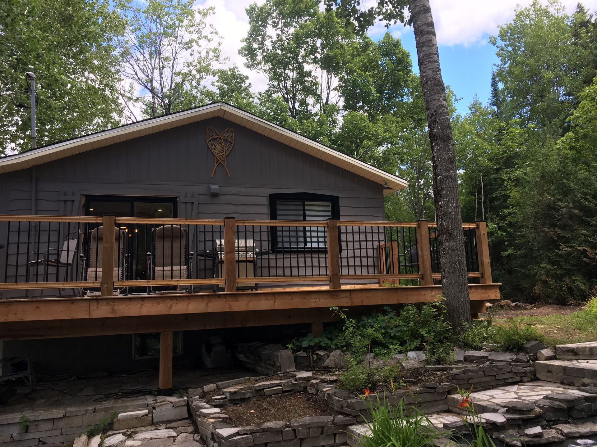 Une petite maison avec une terrasse en bois dans les bois.