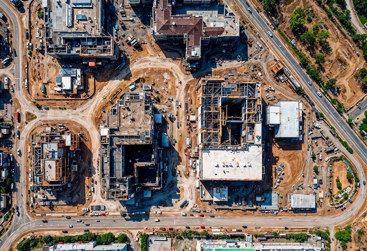 Aerial view of a construction site with multiple buildings under development and dirt roads surrounding it