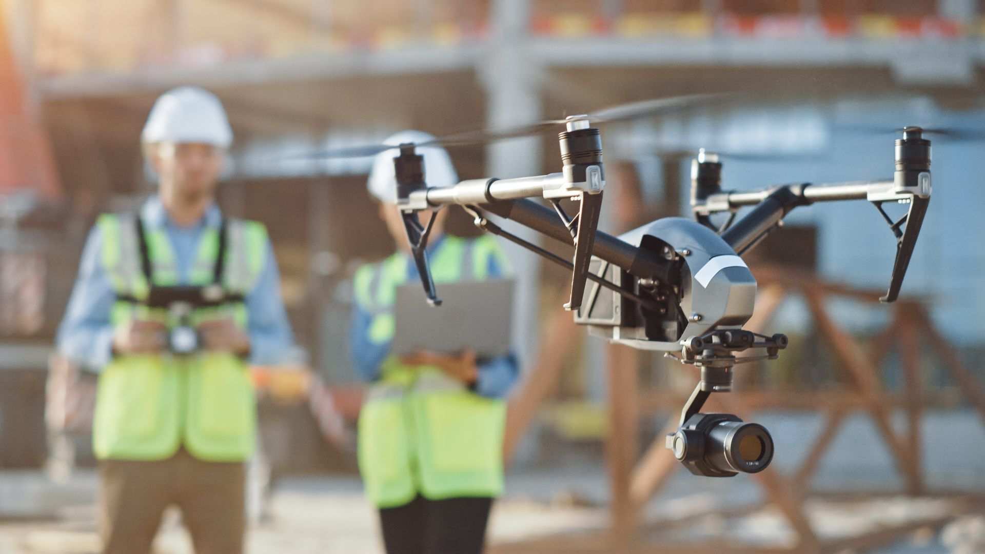 Drone flying in front of two construction workers in safety vests on a building site