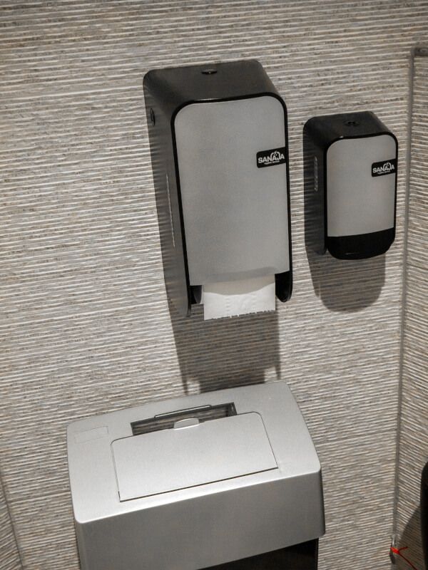 Een toilet met een papieren handdoekdispenser en een prullenbak