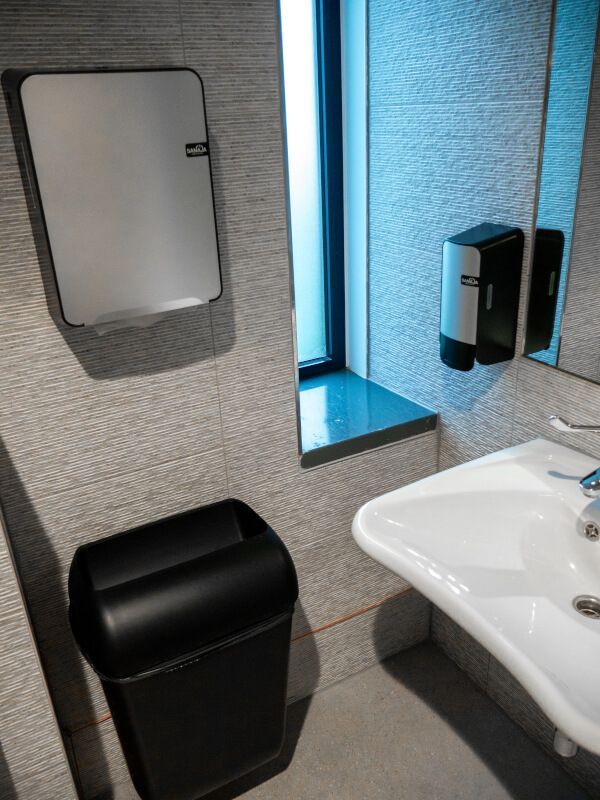 Een badkamer met een wastafel, spiegel en prullenbak