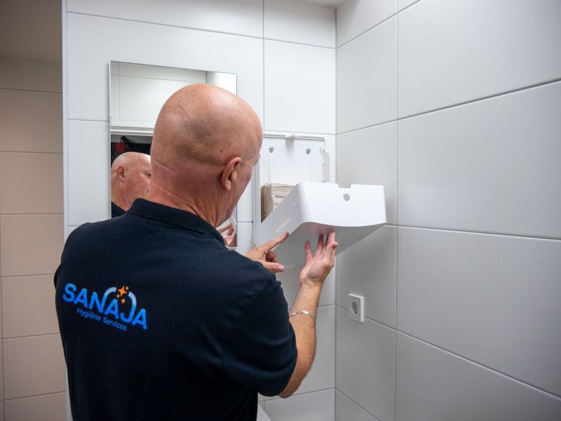 Een man gebruikt een papieren handdoekhouder in een badkamer.