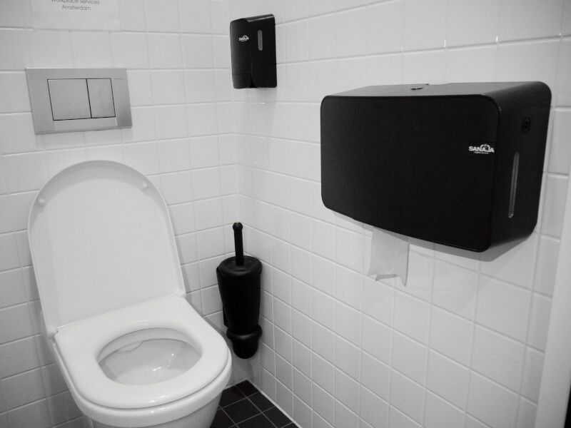 Een zwart-witfoto van een toilet in een openbaar toilet.