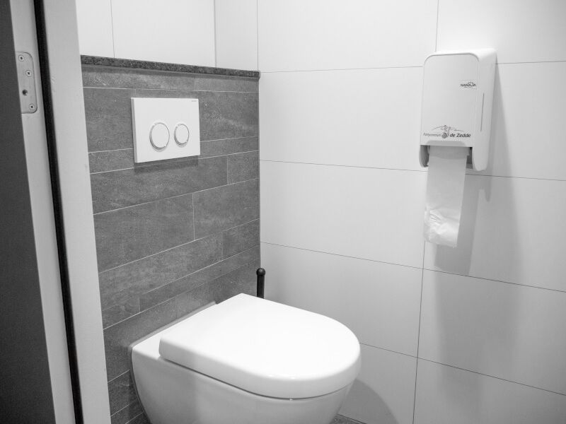 Een zwart-witfoto van een toilet in een badkamer.