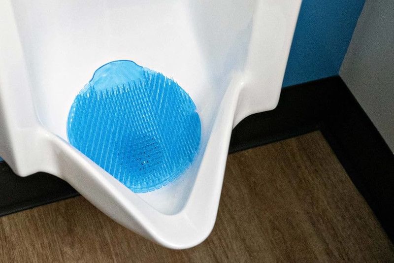 Een urinoir met een blauwe pad erop in een badkamer.