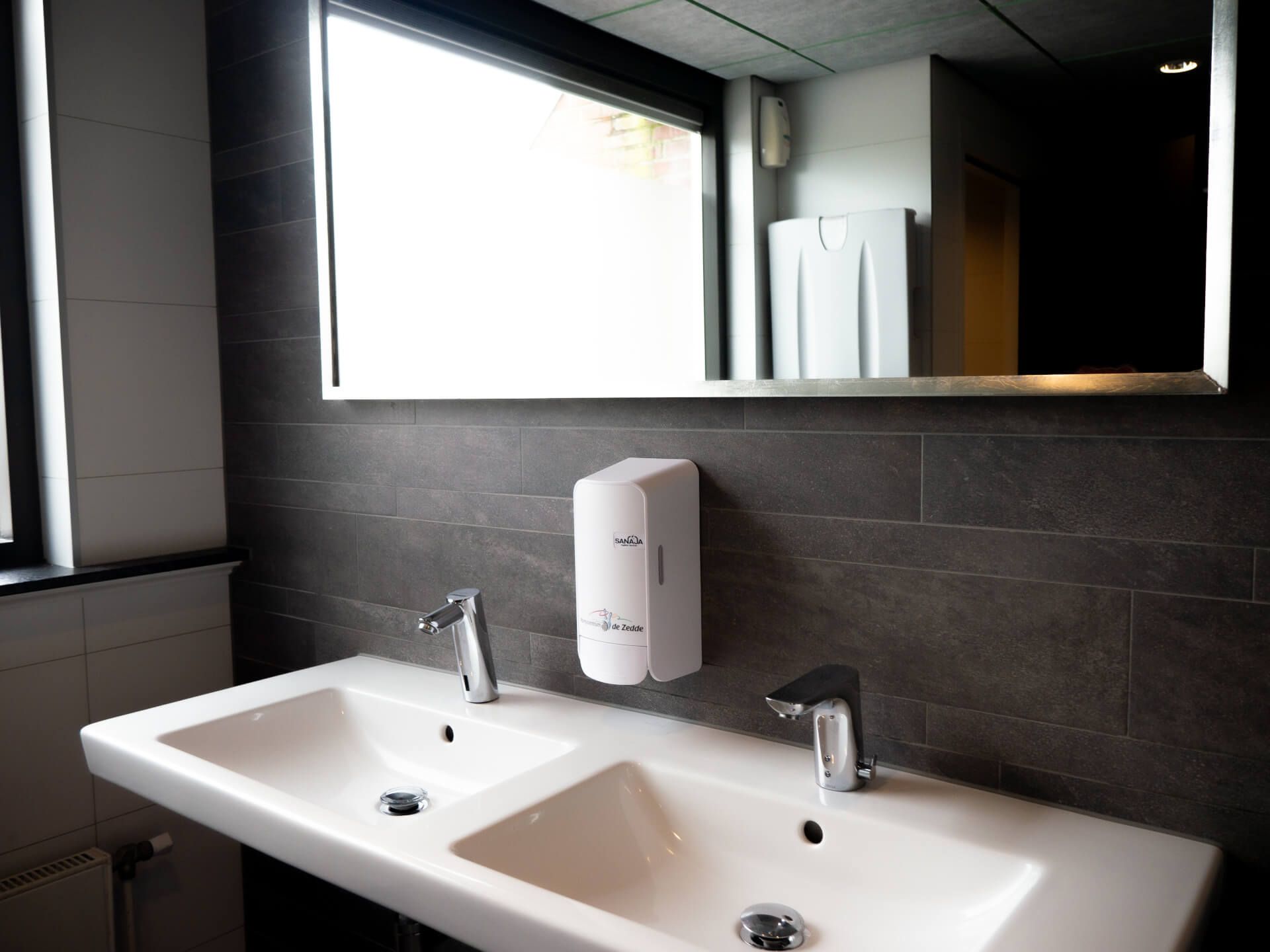 Een badkamer met twee wastafels en een spiegel