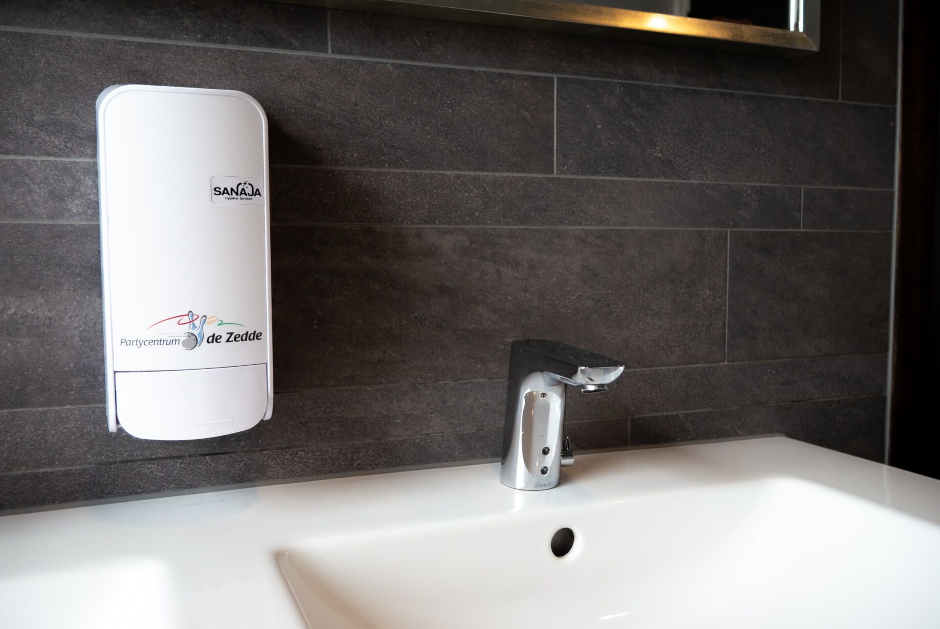 Een badkamerwastafel met een zeepdispenser aan de muur