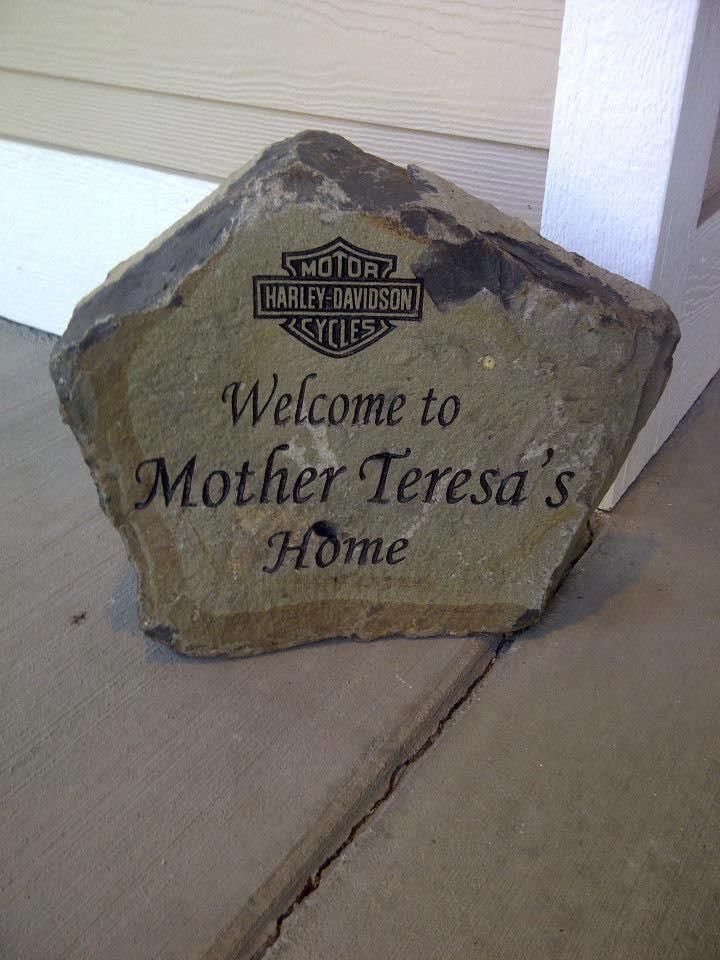 Woman in straw hat smiles, holding wine glass near a lake.