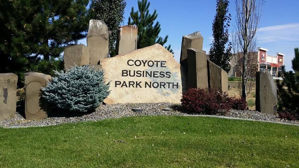 Sign for Coyote Business Park North; stone monument with text in front of green lawn and bushes.