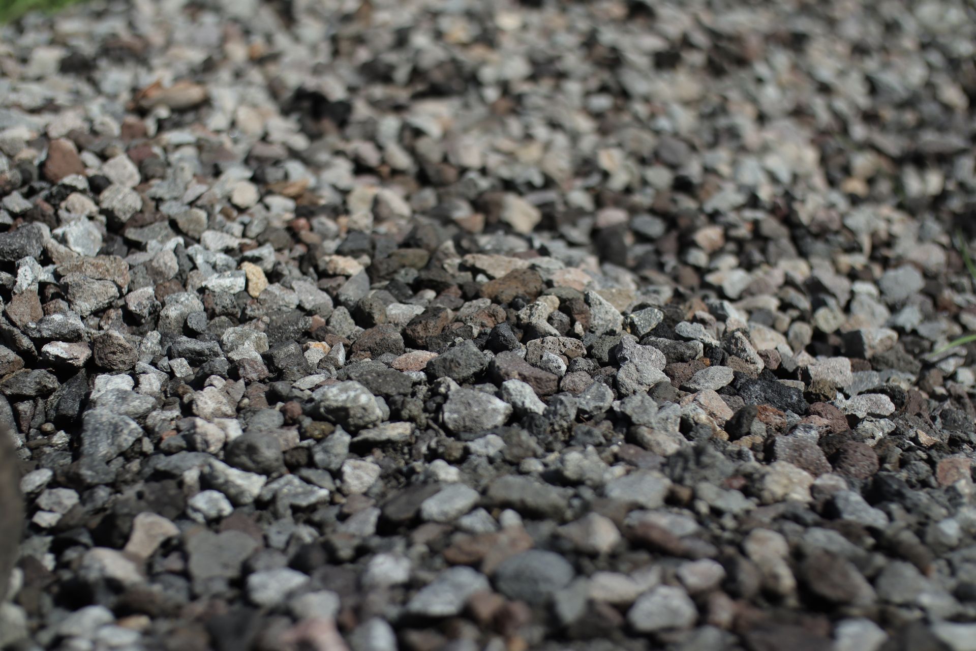 Woman in straw hat smiles, holding wine glass near a lake.