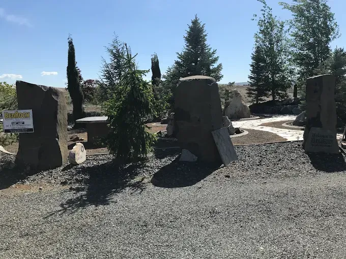Woman in straw hat smiles, holding wine glass near a lake.